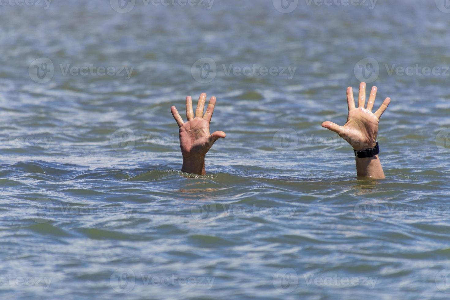 pair of masculine hands sticks out of the sea water photo