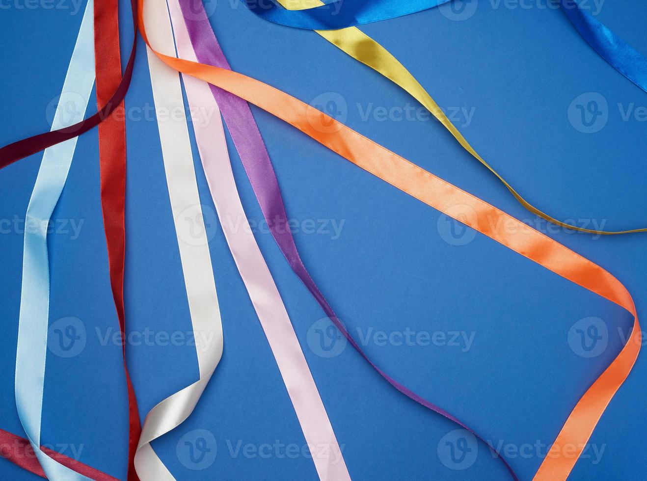 many silk multi-colored ribbons on a blue background photo