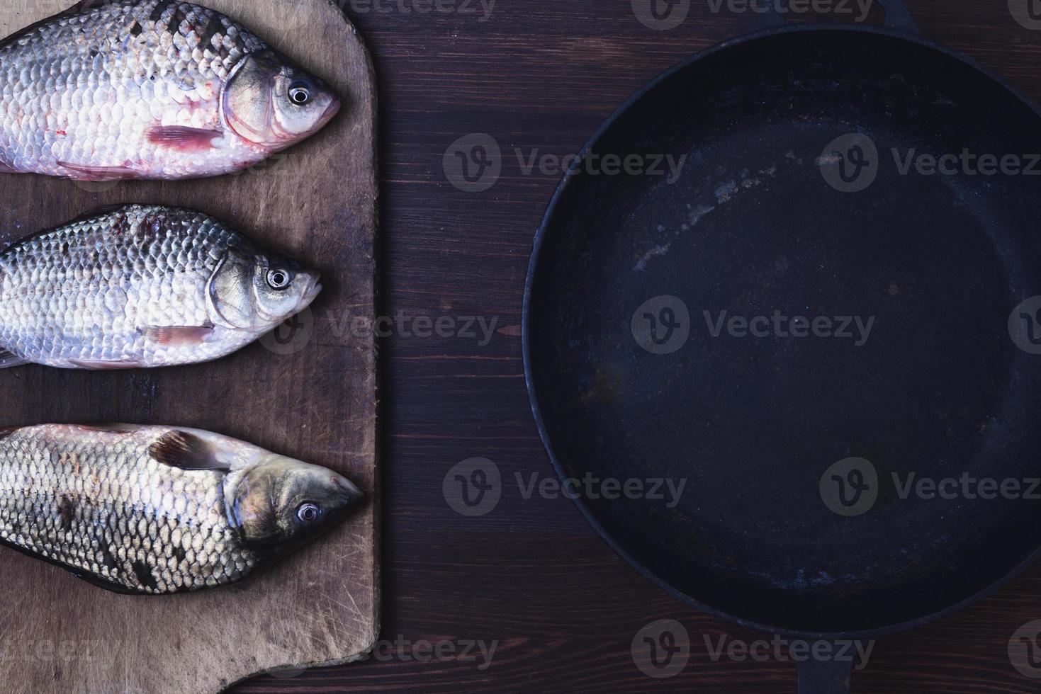 Three live carp fish in a scales on a kitchen board photo