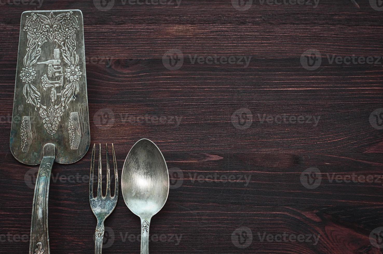 Vintage cutlery on brown wooden surface, top view, an empty space on the right photo