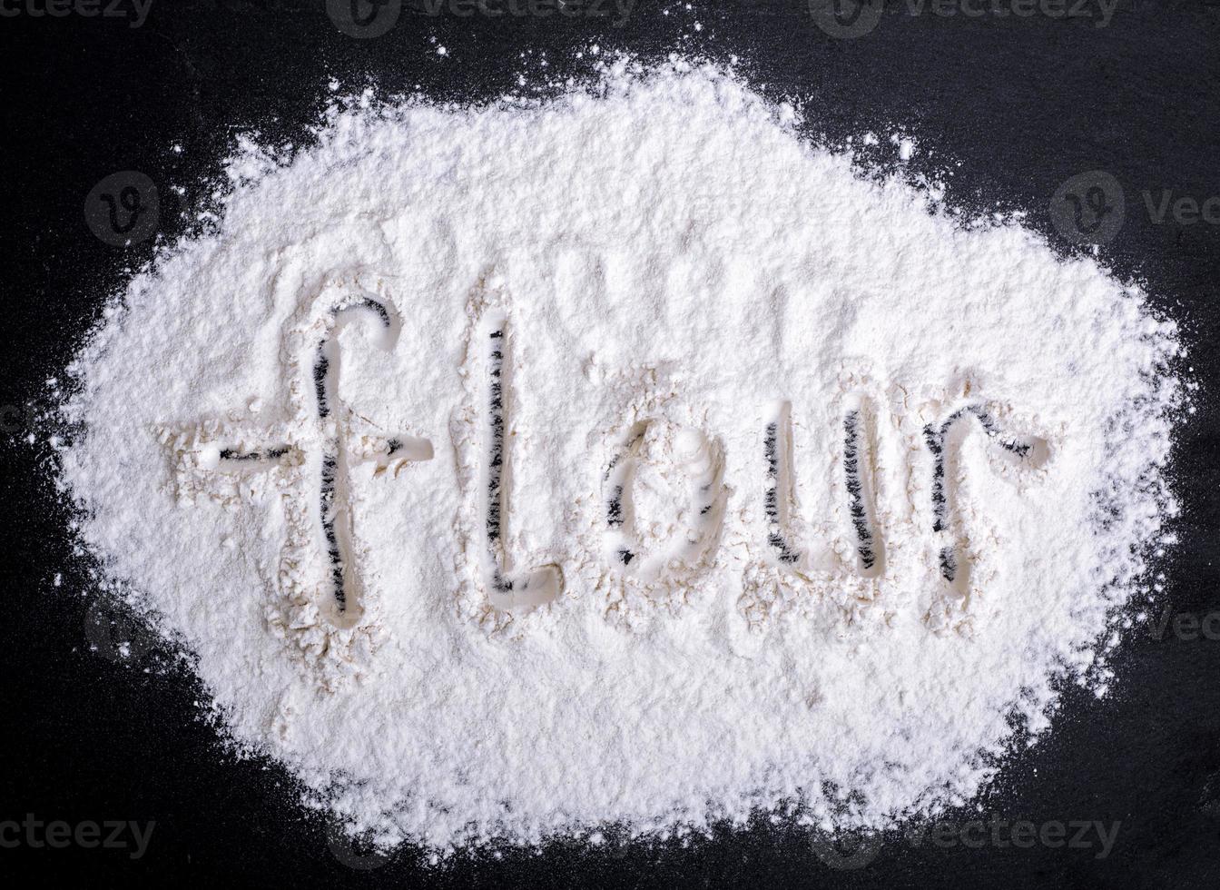 inscription flour on scattered white wheat flour photo