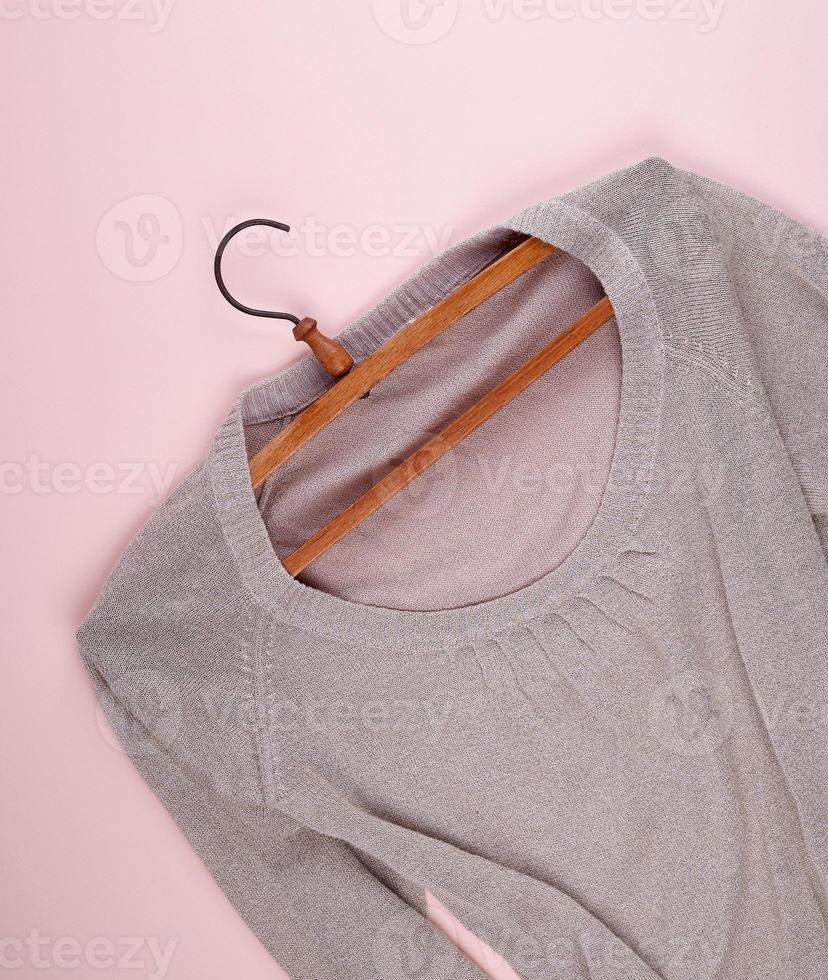 beige female sweater hanging on a vintage wooden hanger photo