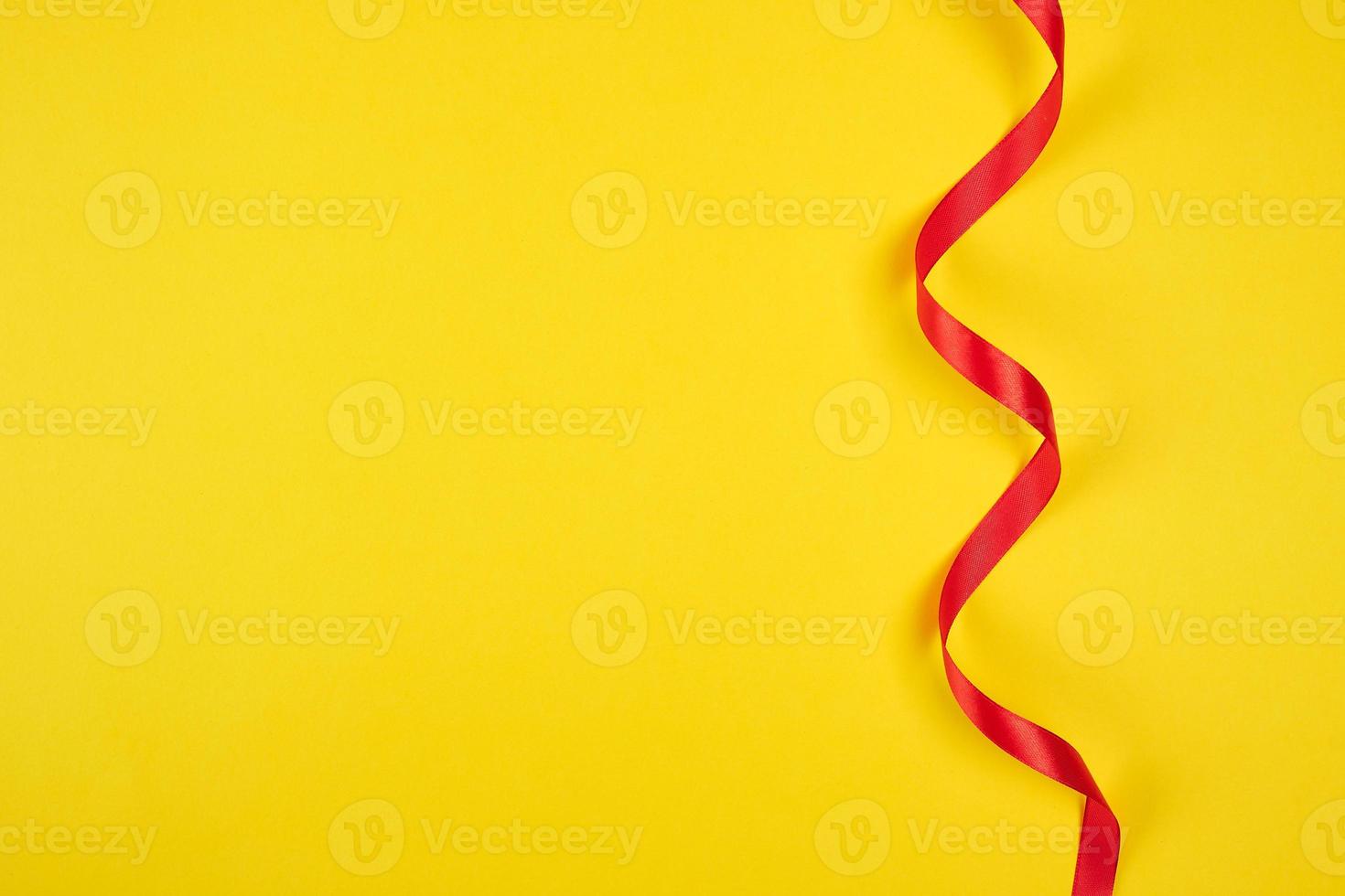 twisted red silk ribbon, yellow background photo