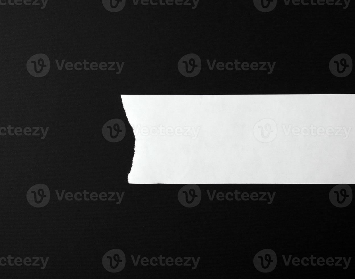 white torn blank strip of paper on a black background photo