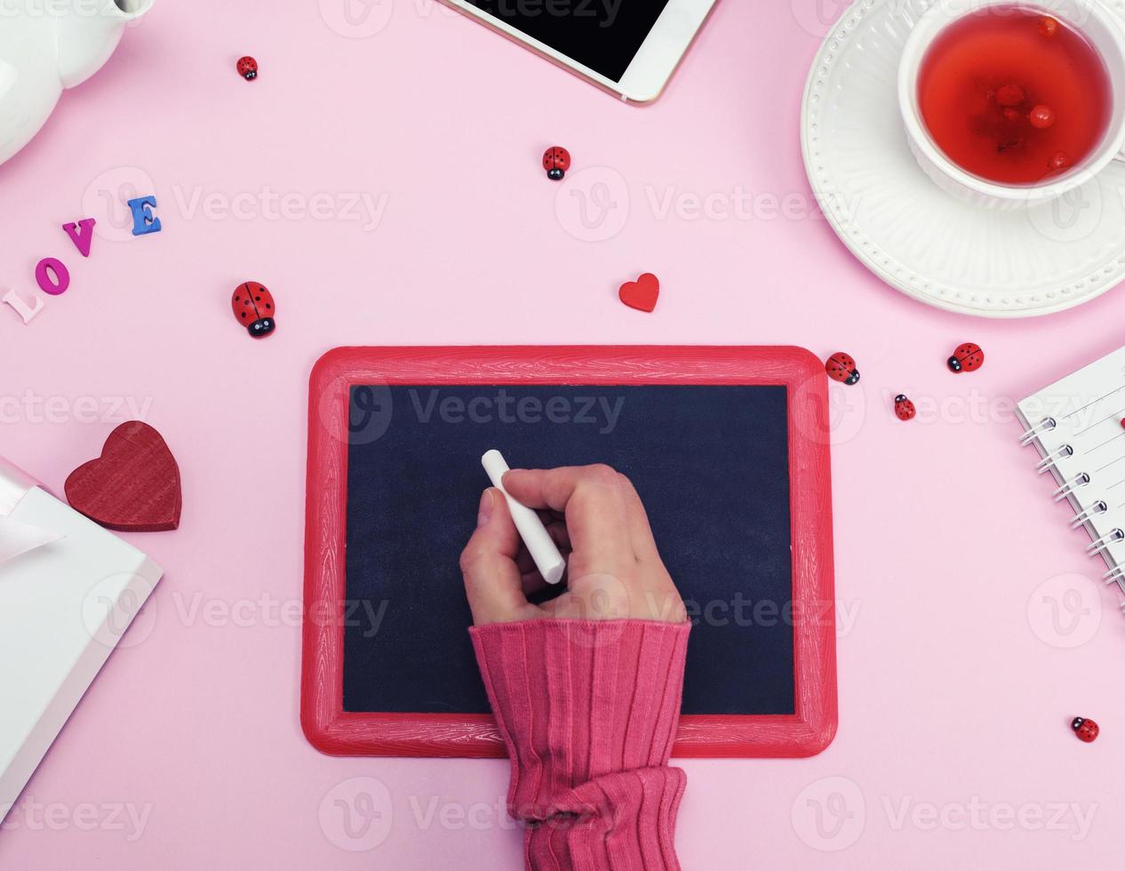 right female hand in a pink sweater with a piece of white chalk photo