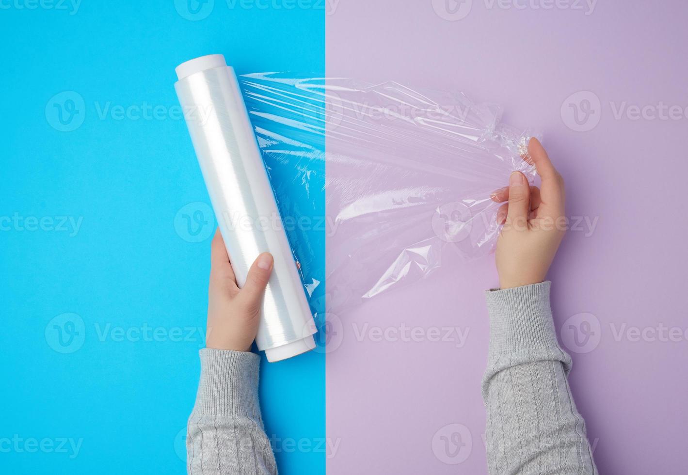 two hands hold a large roll of wound white transparent film for wrapping food photo