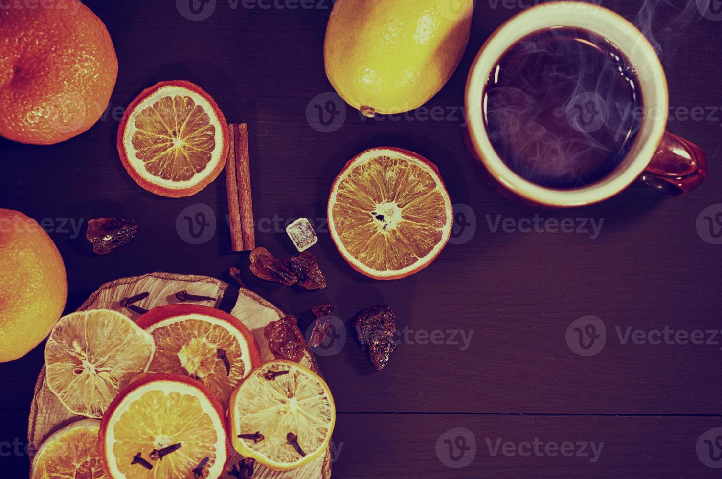 Tea in a mug with dried citrus fruit and spices on a black wooden surface photo