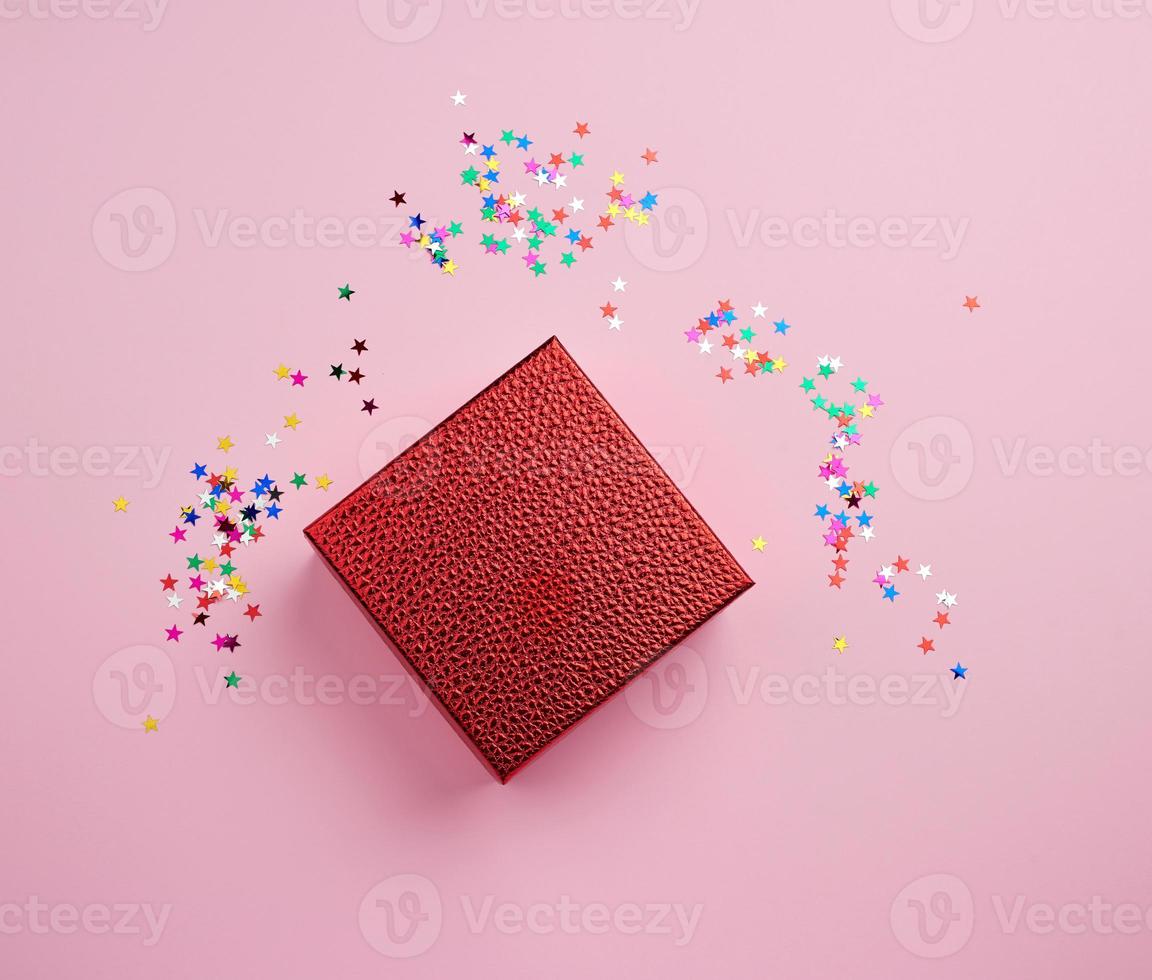 square red shiny box and multicolored sparkles on a pink background photo