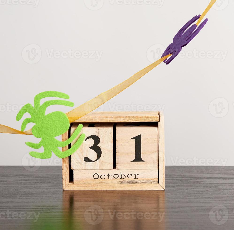 wooden calendar of cubes with the date October 31 on a black table, celebration of Halloween photo