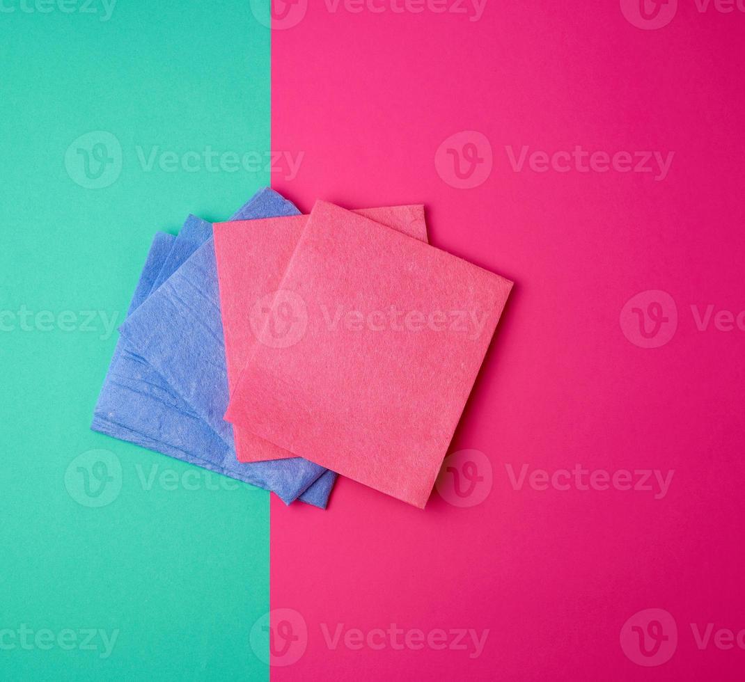 multi-colored square dishwashing sponges on a pink green background photo