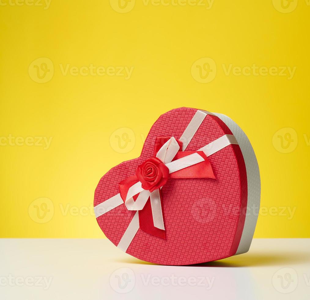 heart shaped red cardboard gift box on white table, festive backdrop photo