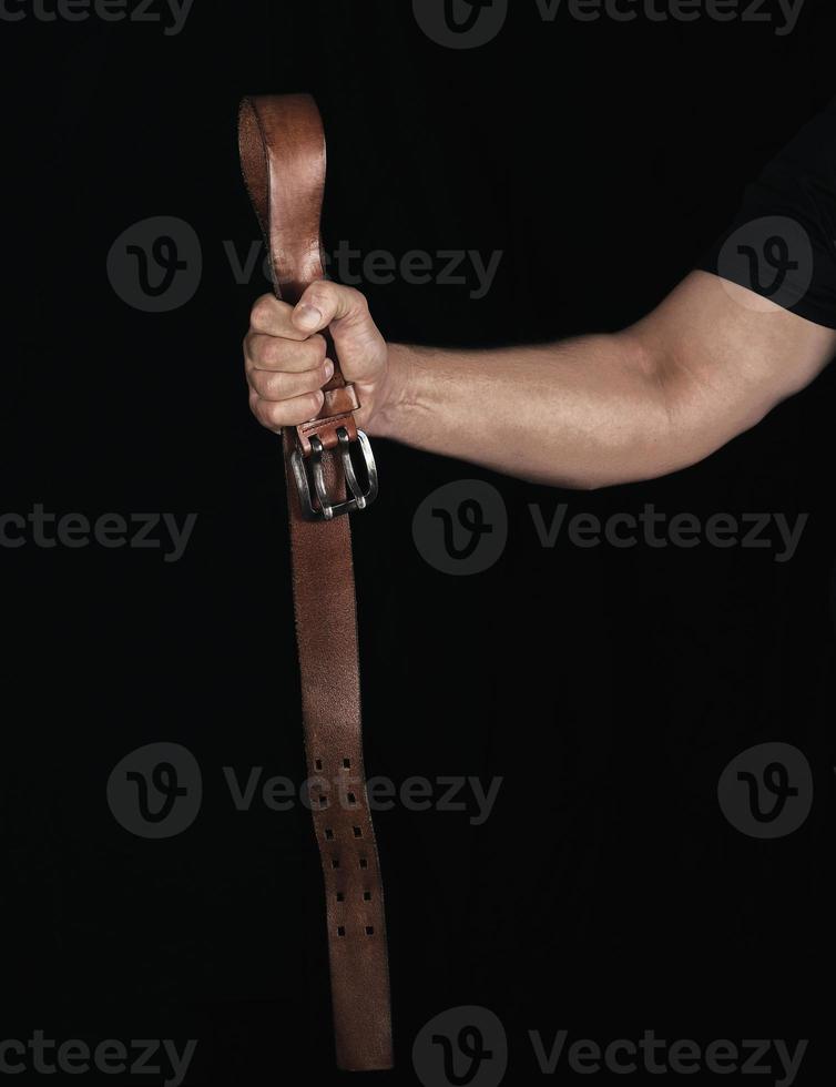 brown leather belt with an iron buckle in a man's hand photo