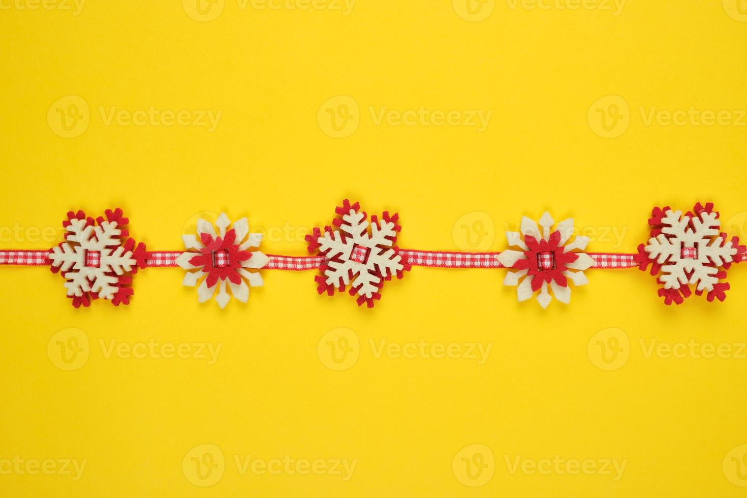 Christmas garland with carved felt snowflakes on a red ribbon photo