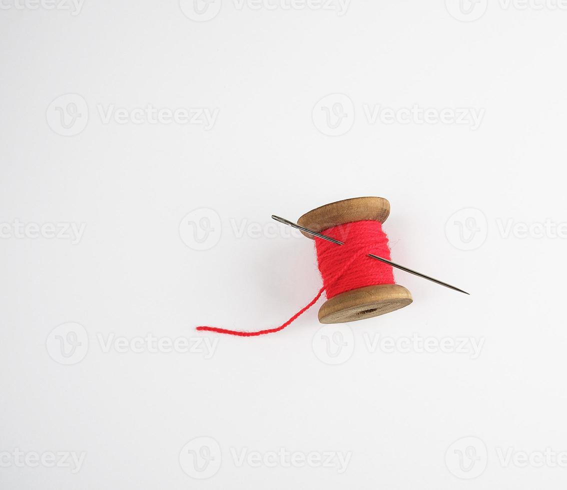 wooden reel with red wool thread and a large needle photo
