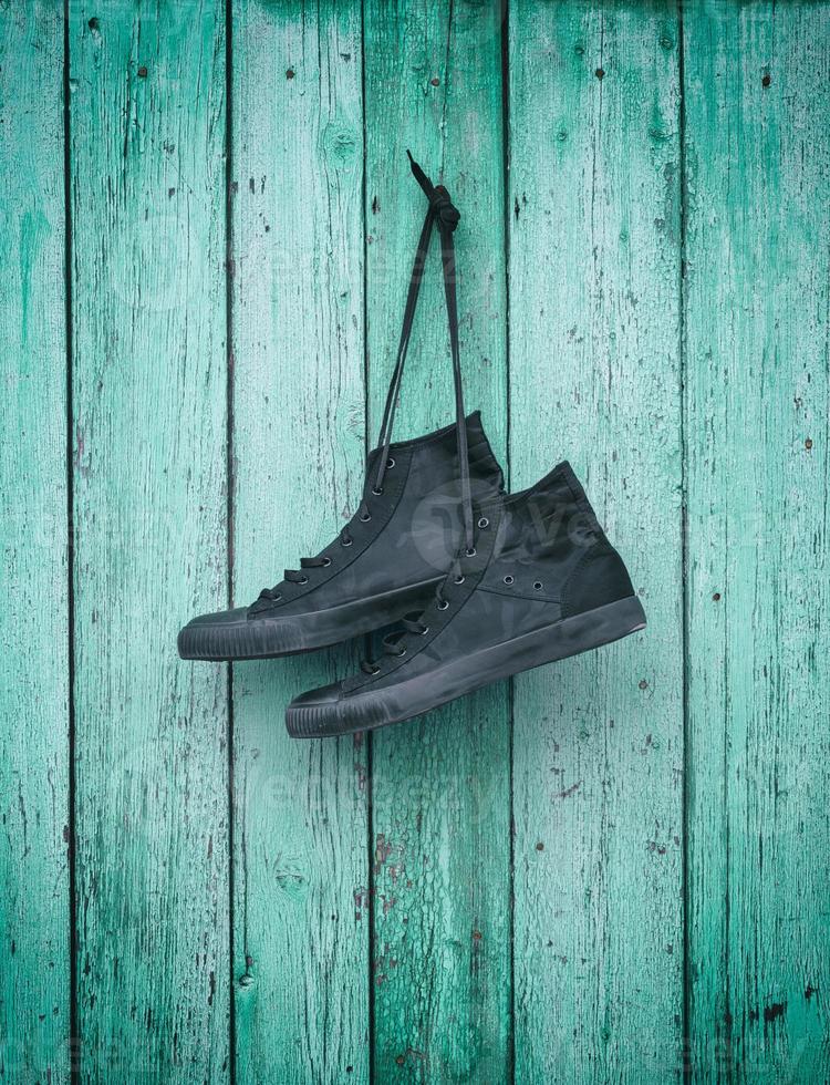 textile sneakers hanging on a green wooden wall photo