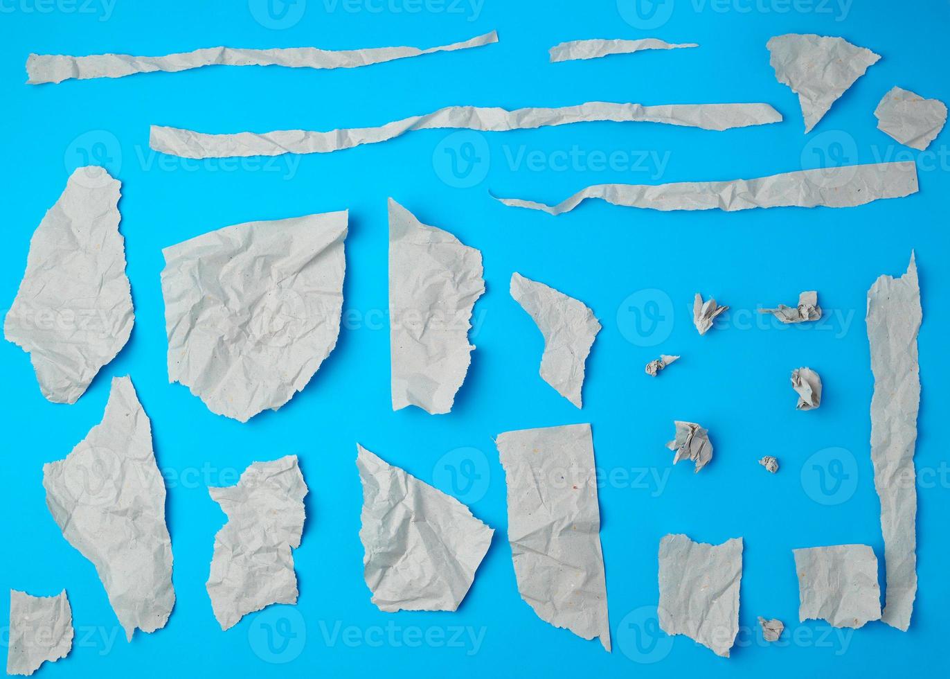 set of various pieces of torn gray crumpled paper on a blue background photo