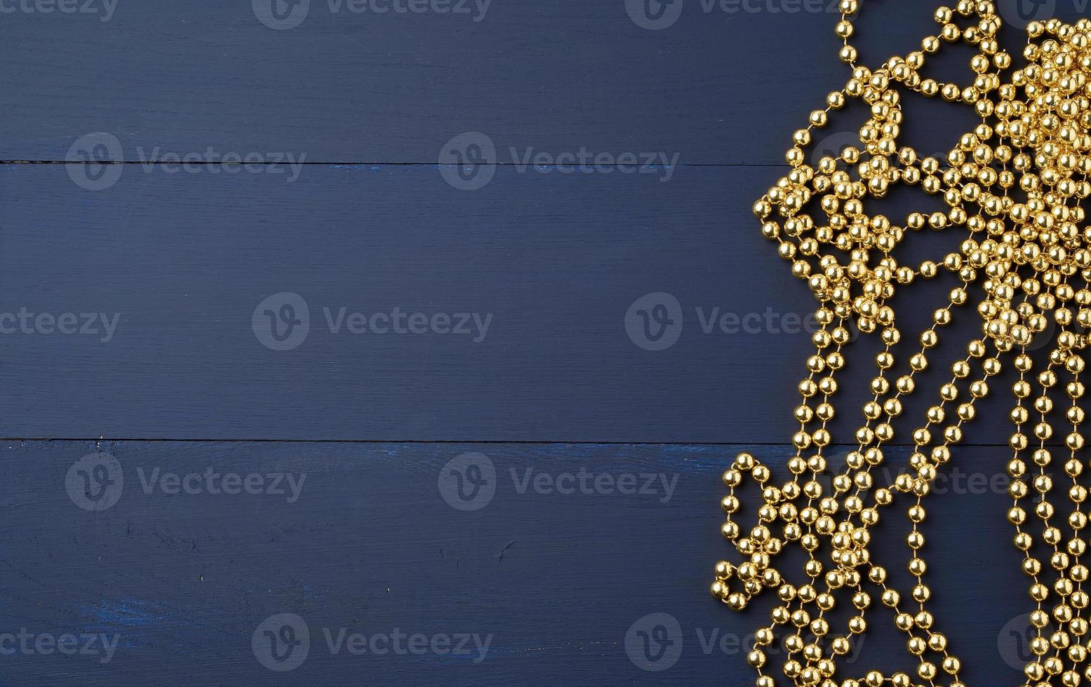 Christmas garland of round golden beads strung on a string, blue wooden background from board photo