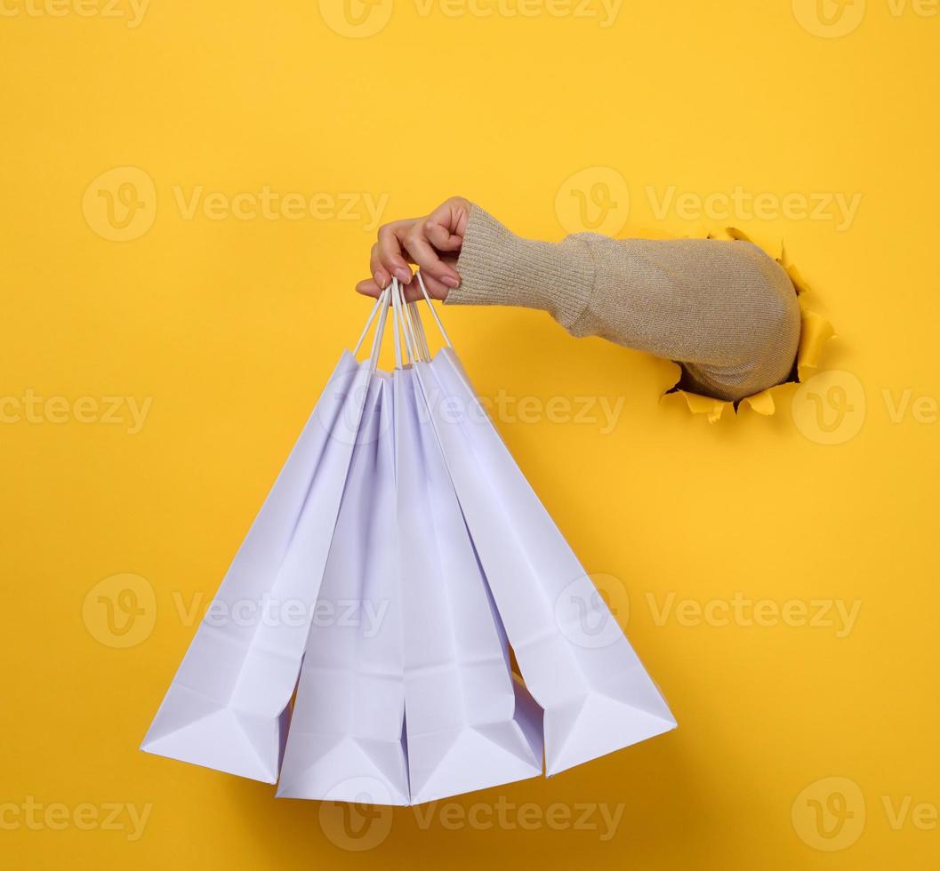 female hand holds a white paper disposable bag with handles for groceries and clothes. Recyclable packaging. Zero waste. Sale photo
