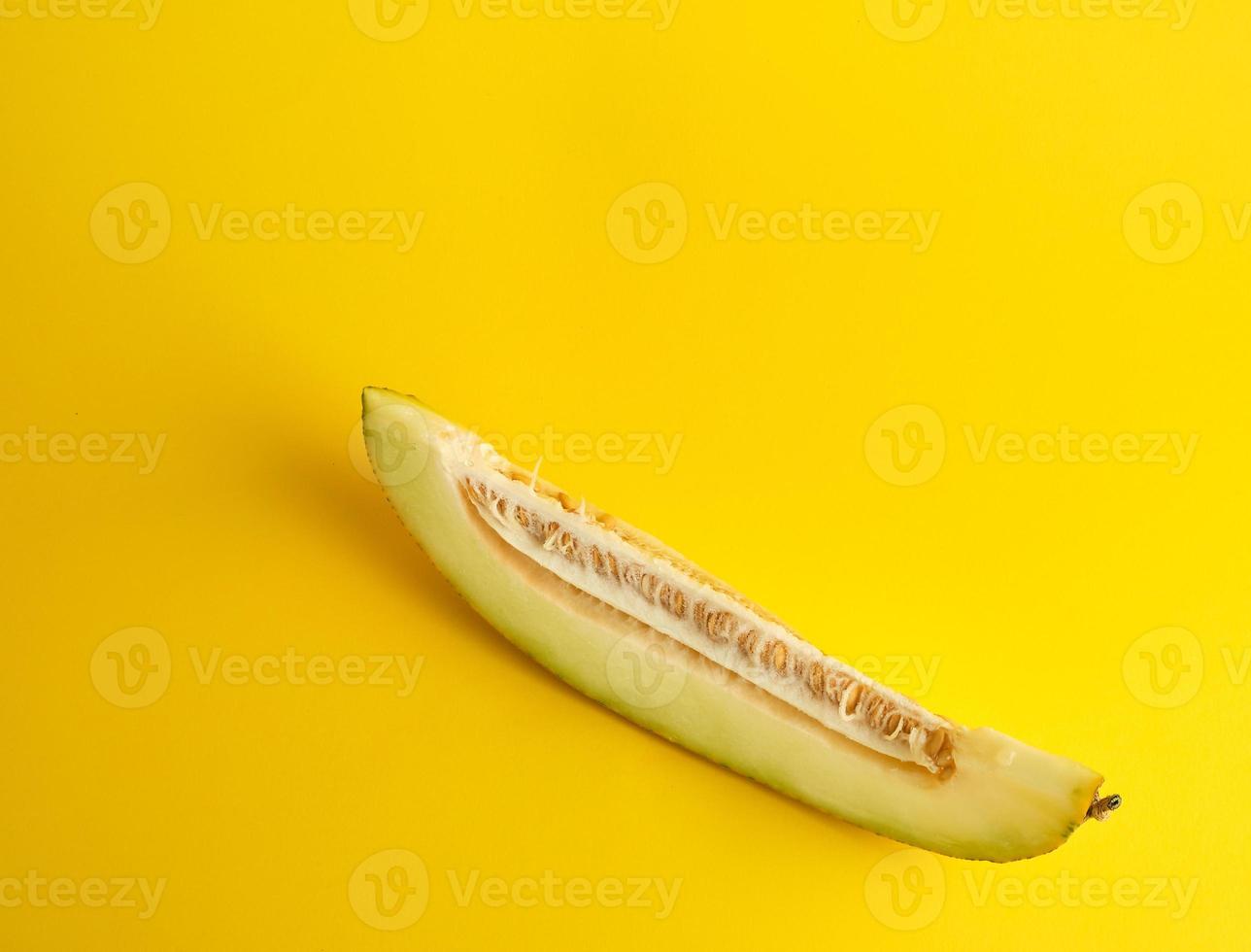 piece of ripe melon with seeds on a yellow background photo