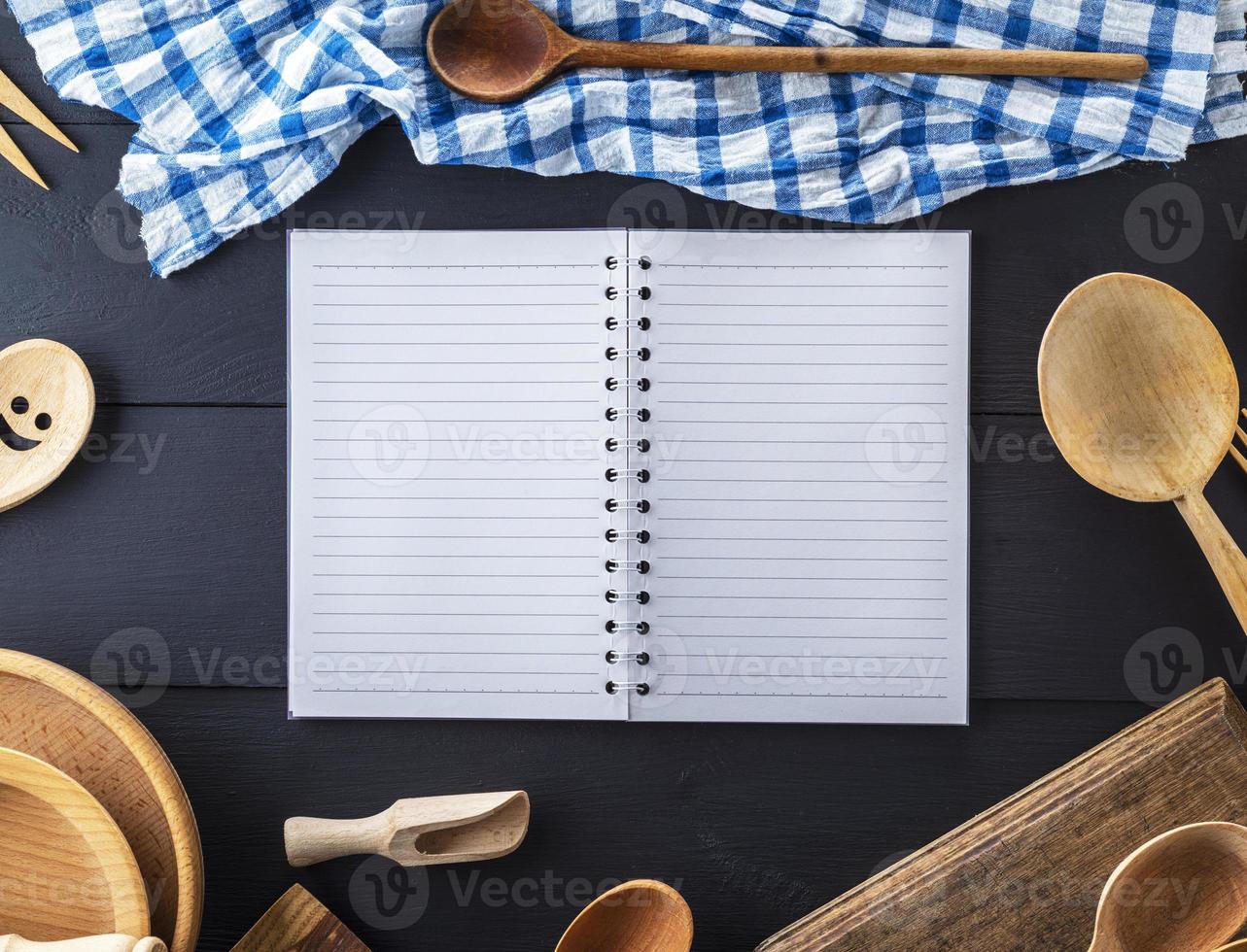 cuaderno abierto en blanco en línea y accesorios de cocina de madera foto