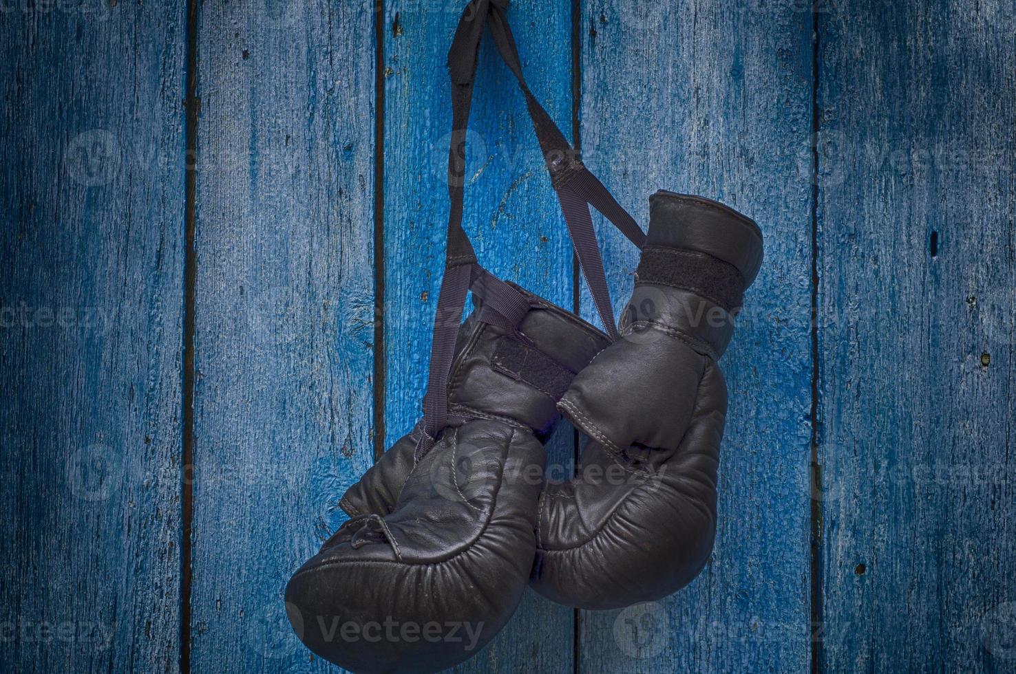 par de guantes negros para el boxeo tailandés colgando de un clavo foto