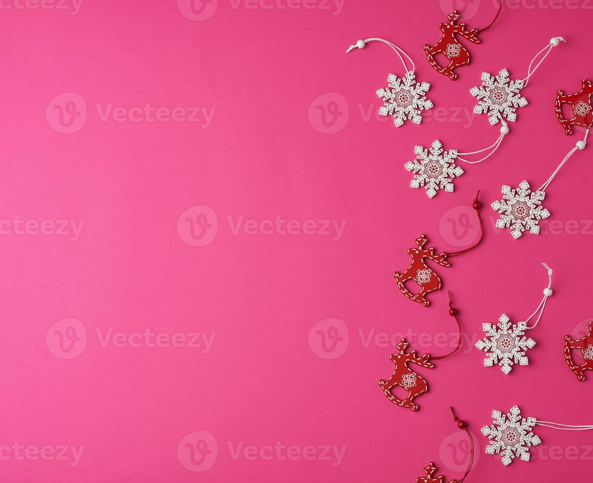 wooden carved Christmas decorations for the holiday tree on a pink background photo