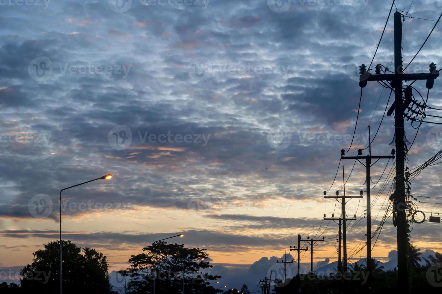 silhouette photo of electric poll with line or wire and many small birds on top taken in the early morning or evening in Thailand upcountry with overcast sky, Upcountry landscape scenery