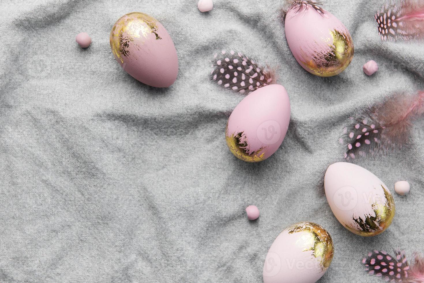 los huevos de pascua están pintados con pintura violeta y dorada sobre un fondo de lino gris. foto