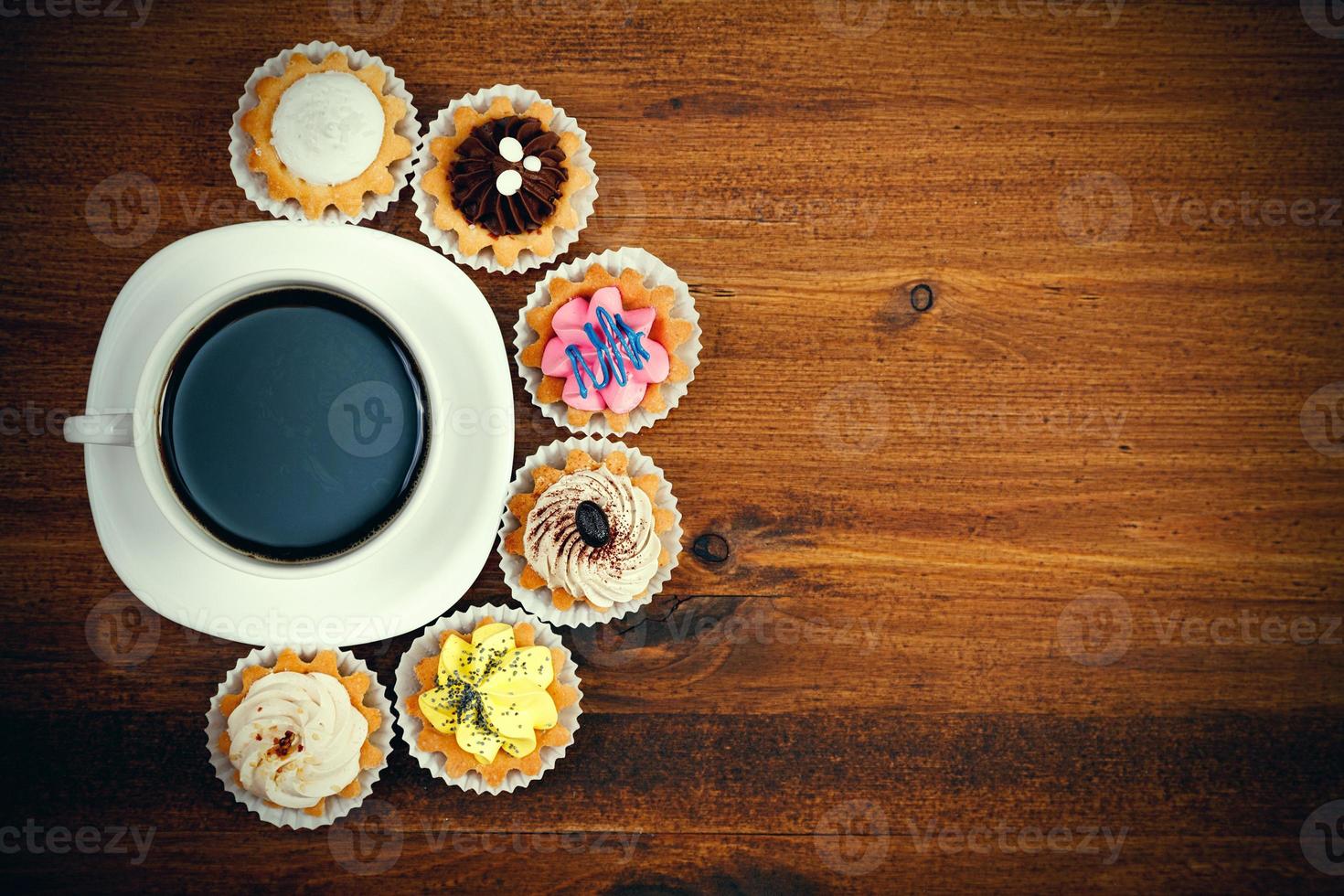 Closeup shot of small cup of coffee with colorful cupcakes. Flat lay style photo