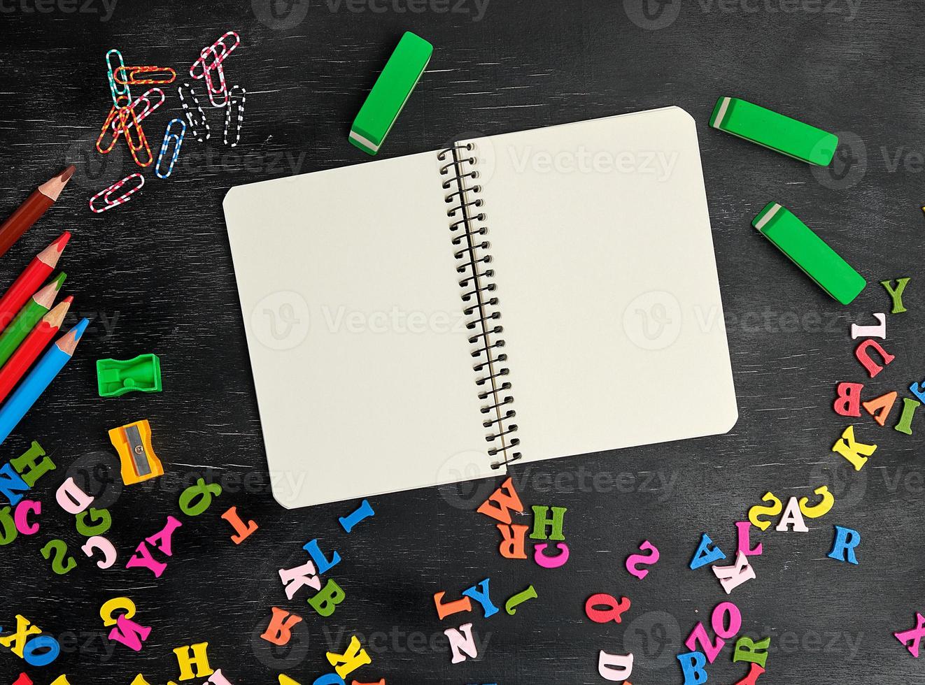 open spiral notebook with clean white sheets, wooden colored pencils photo