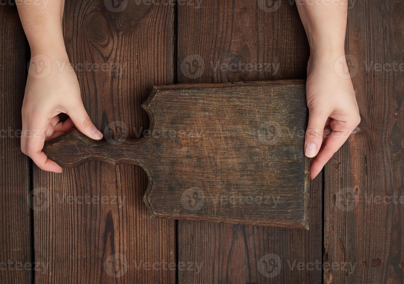 two hands holding a vintage brown empty kitchen cutting board with a handle photo