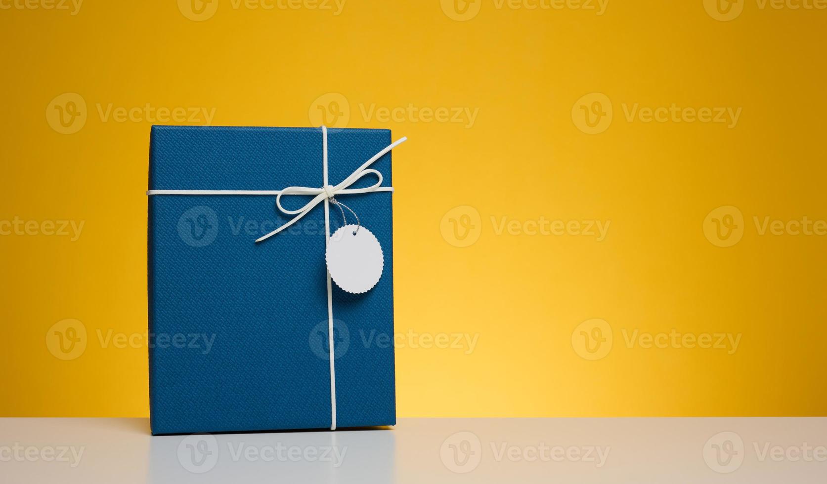 Blue cardboard gift box on yellow background photo