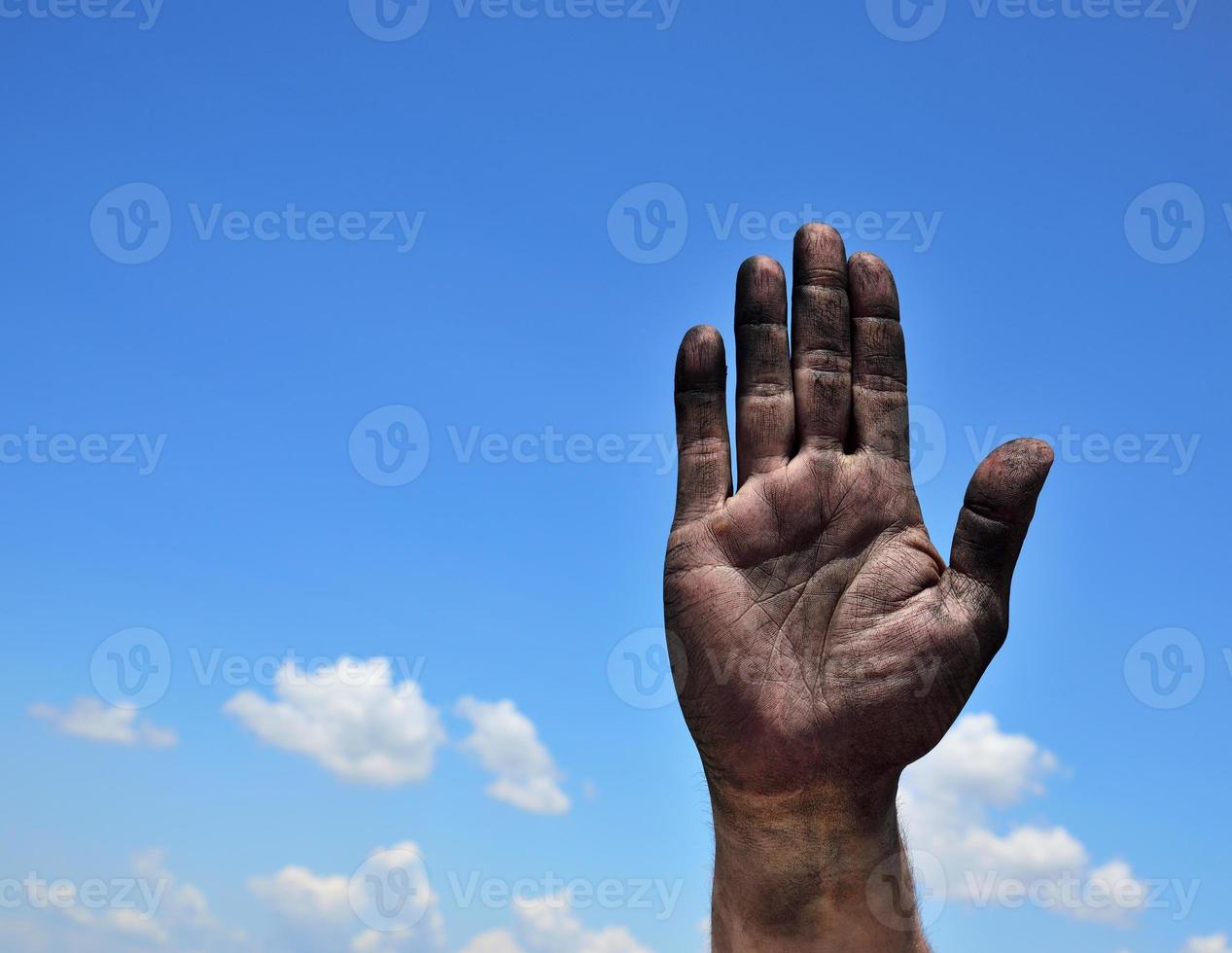 Dirty male palm raised up against a blue sky photo