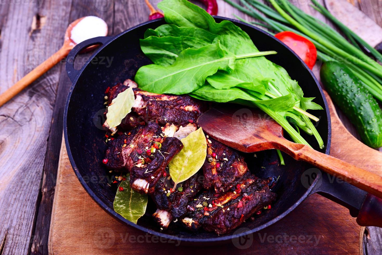 costillas de cerdo fritas en una sartén negra de hierro fundido, carne marinada en especias foto