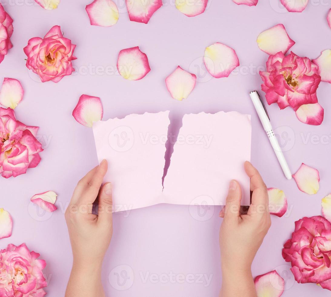 two hands hold an empty pink sheet torn from a notebook photo