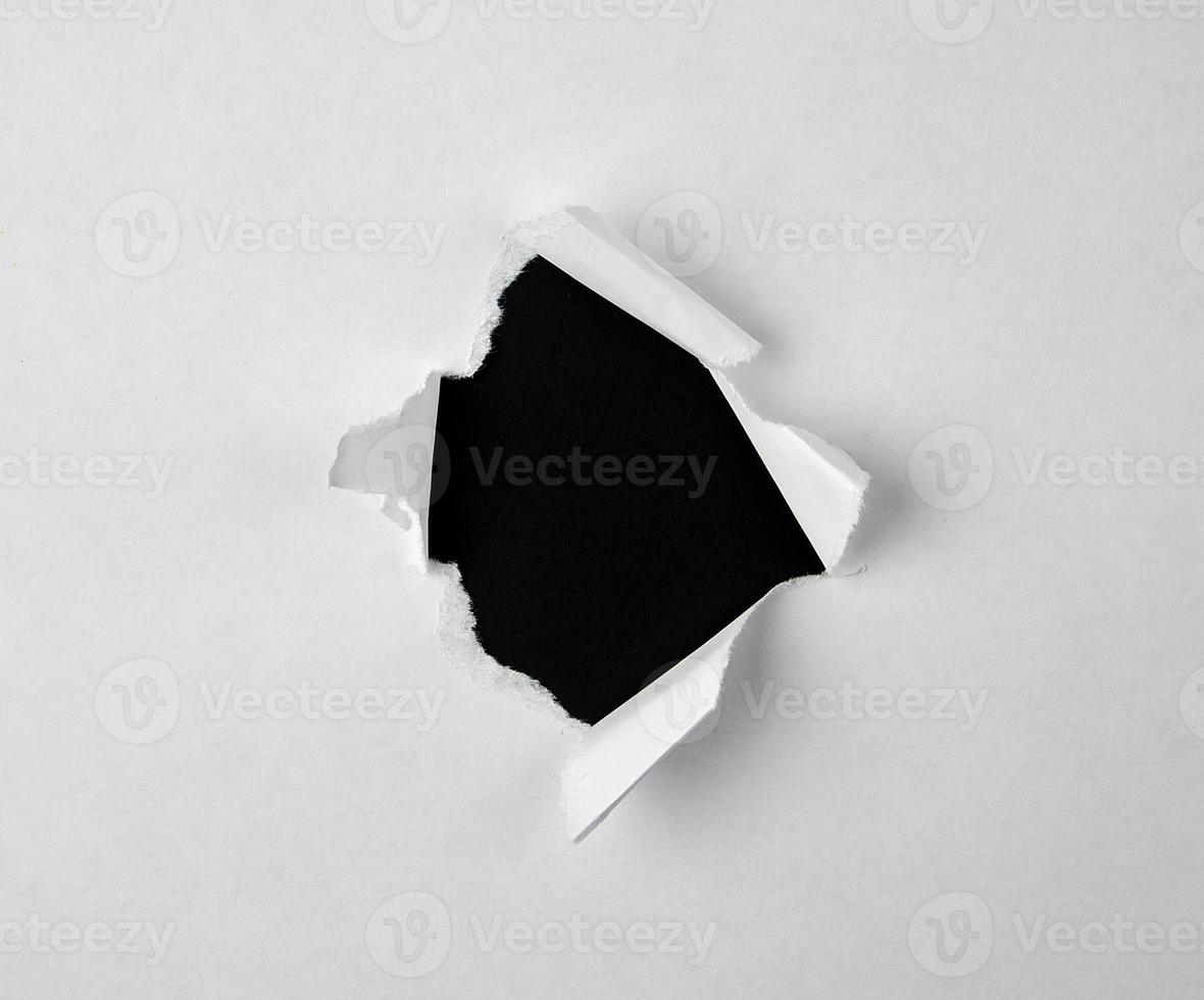 round torn hole with twisted edges in white paper photo