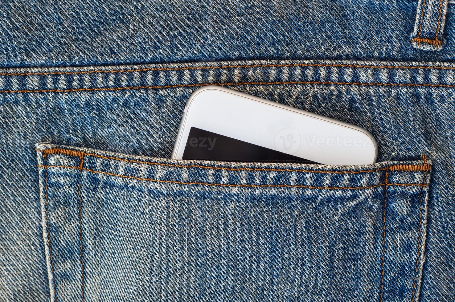 teléfono inteligente en el bolsillo trasero de los jeans foto