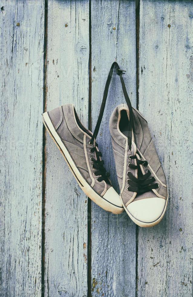 old male blue sneakers hang on a nail photo