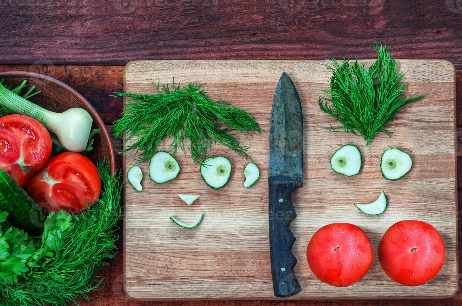 Fresh tomatoes and cucumber in a bowl and on a kitchen board photo