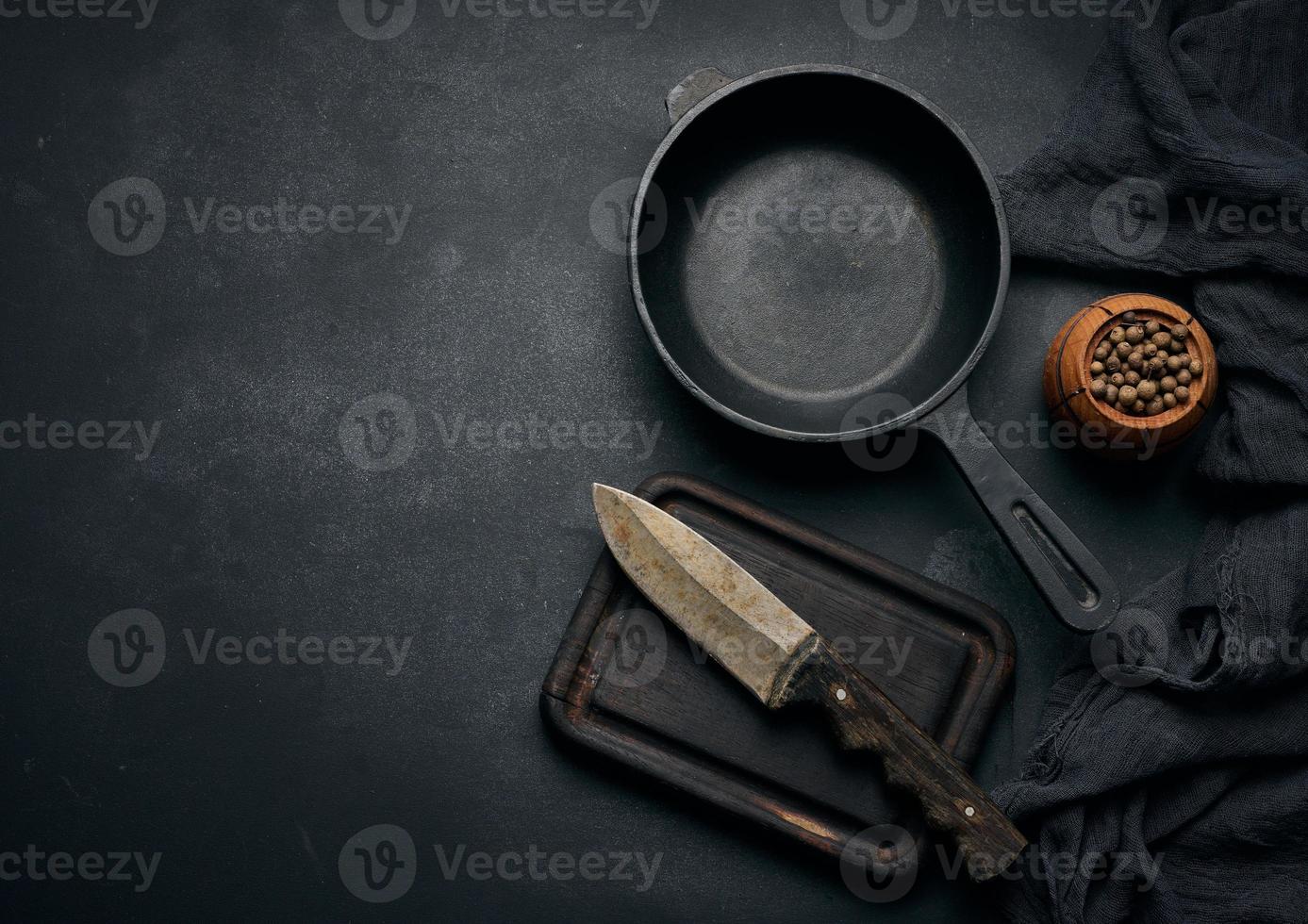 Empty round cast iron frying pan with wooden handle on black table, top view photo