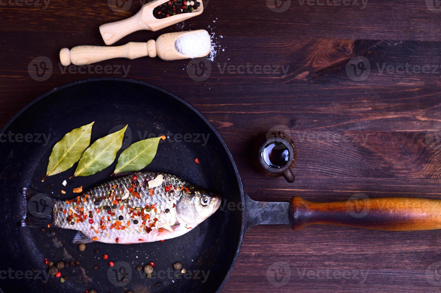 Carp in spices on a black cast-iron frying pan photo