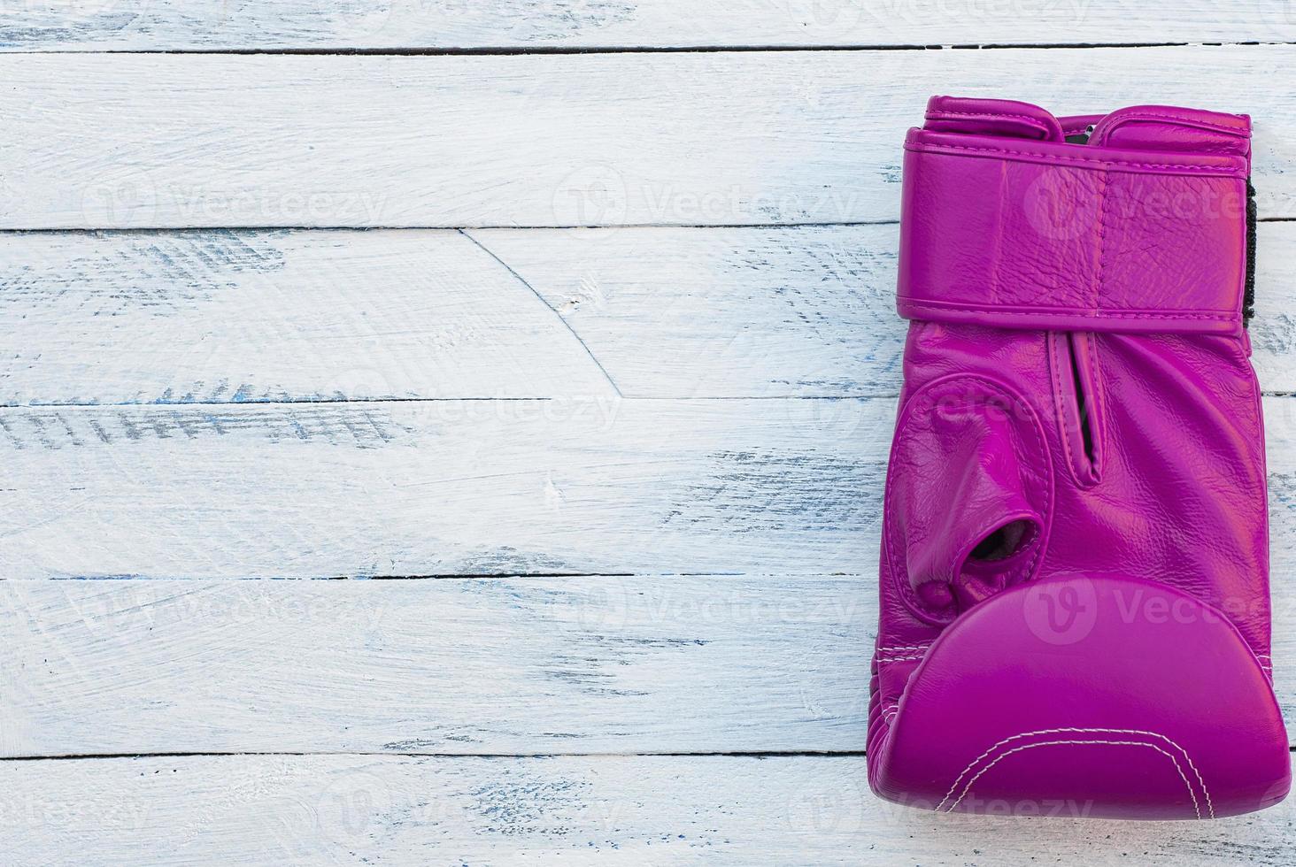 One pink boxing glove on a white wooden surface photo