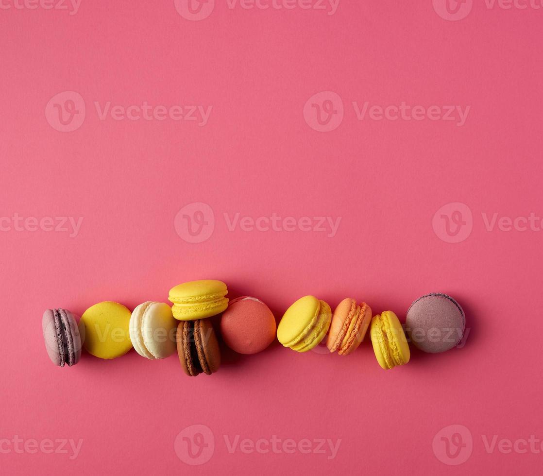 round multi-colored baked macarons with cream lie in a line photo