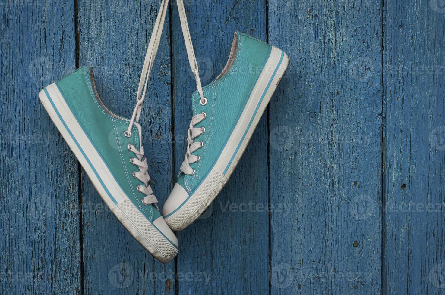 Turquoise youth sneakers hanging on a nail photo