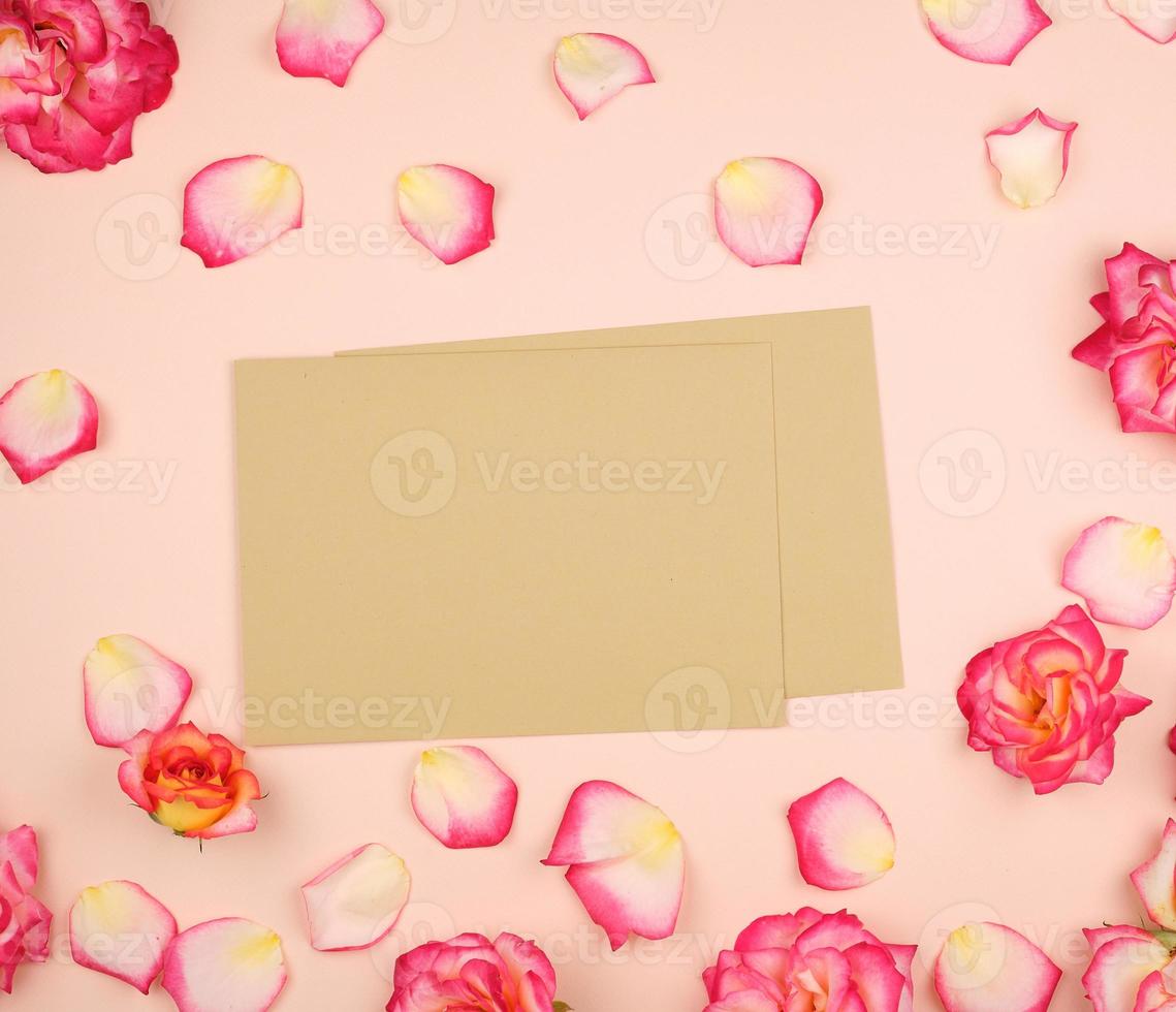 pink rose buds and brown paper envelope on a beige background photo