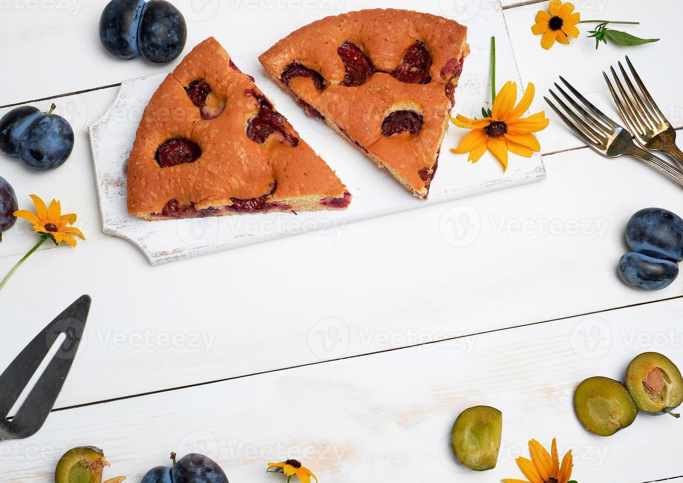 slices of biscuit plum cake on a white wooden board and fresh fruits photo