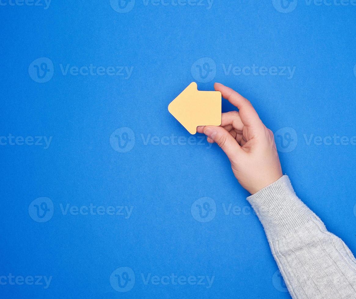 hand holds an orange paper sticker in the form of an arrow pointer photo