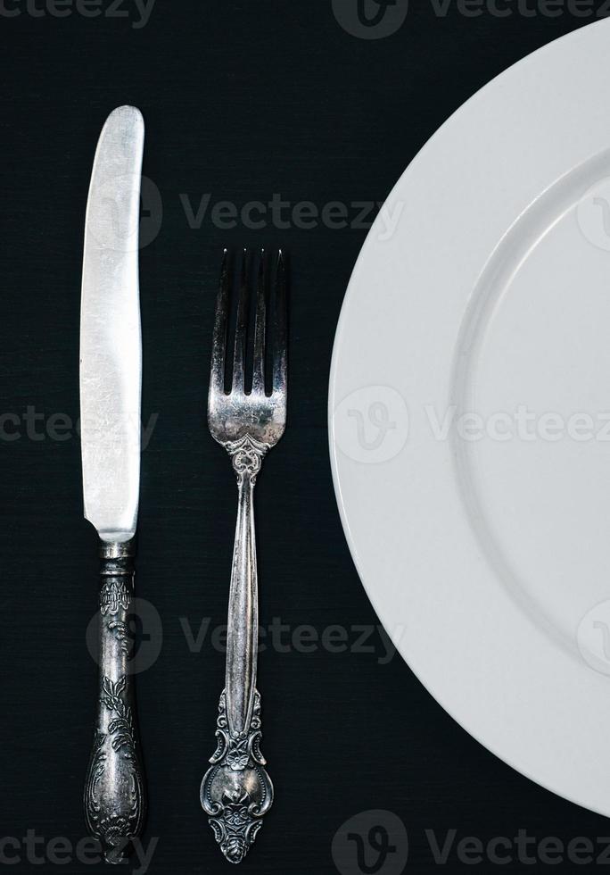 platos blancos medio vacíos, cuchillo vintage y tenedor en la mesa foto