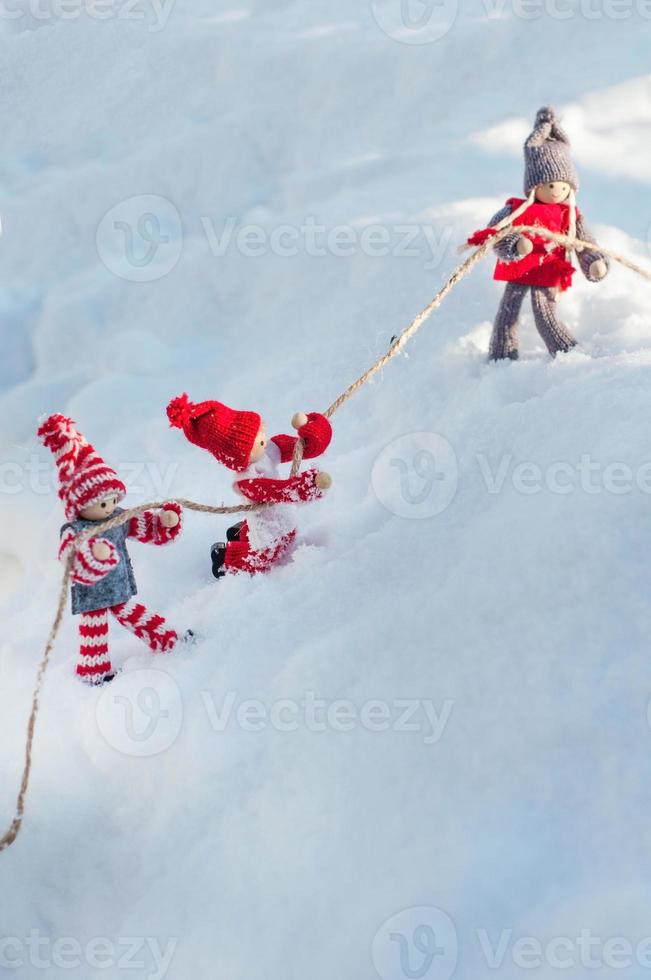 wooden dolls on a snowy slope clinging to a rope photo