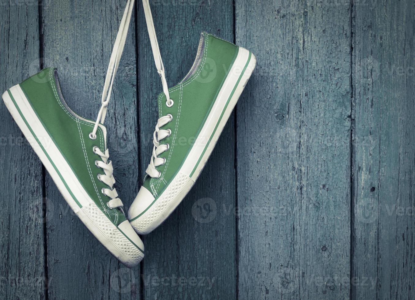 Green youth sneakers hanging on a nail photo